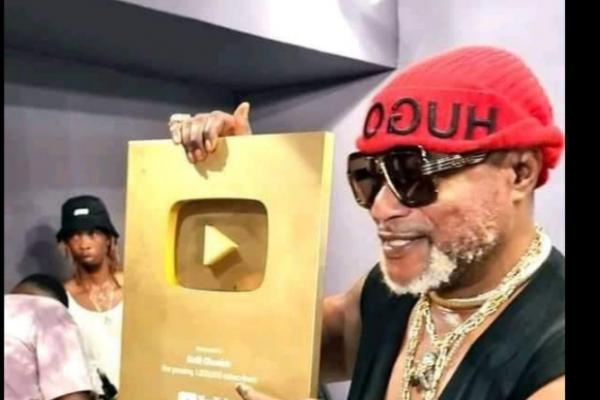Koffi Olomide brandissant son trophée de créateur d'Or Youtube.