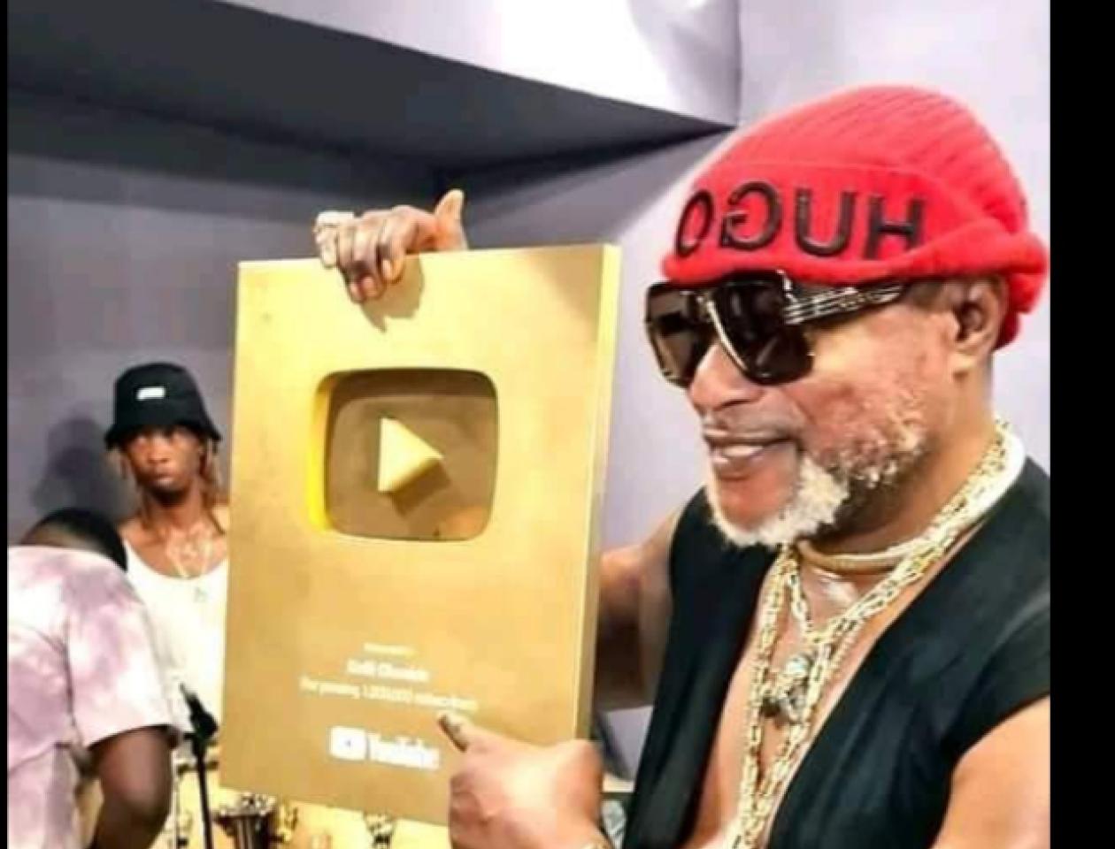Koffi Olomide brandissant son trophée de créateur d'Or Youtube.